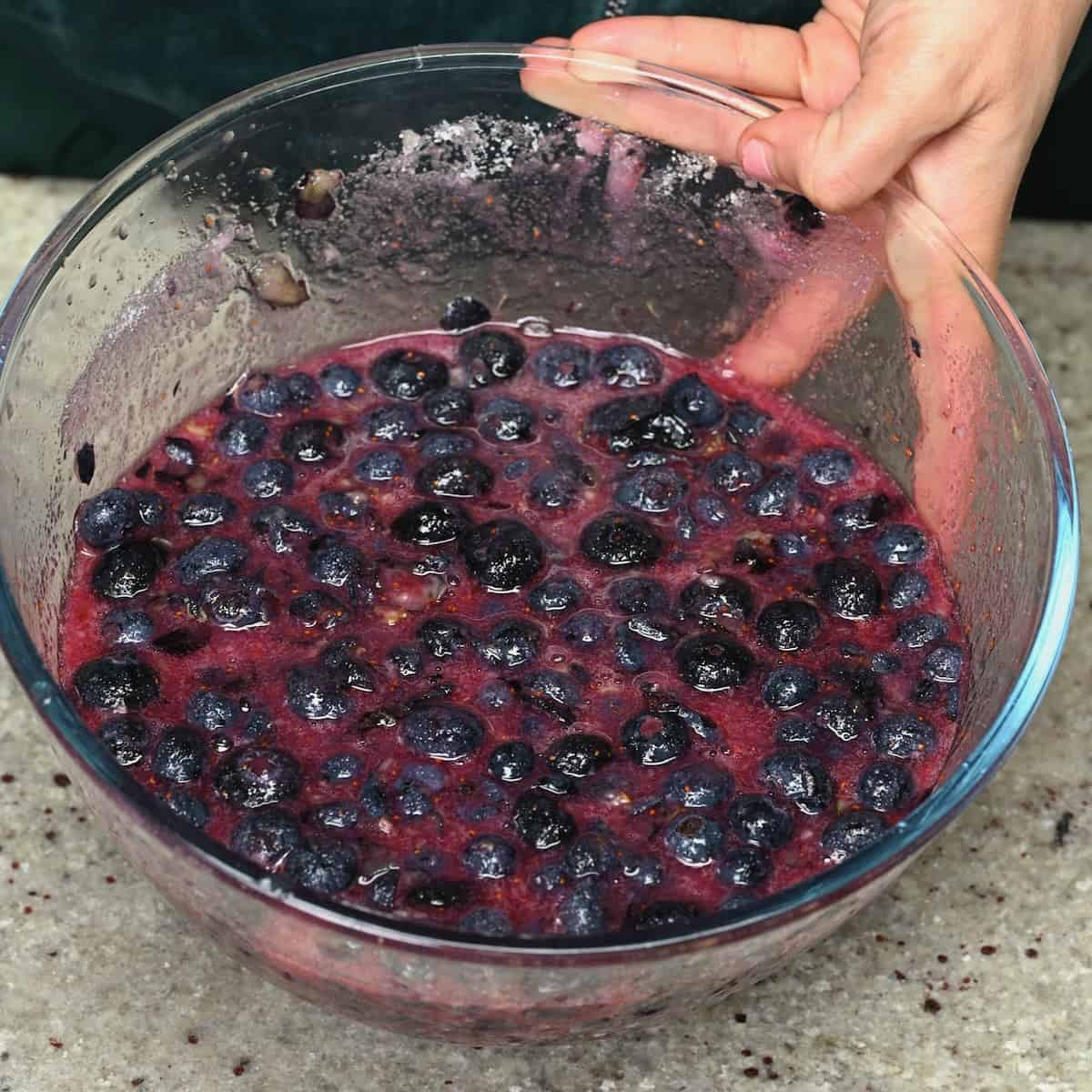 Blueberries mixed with sugar and lemon juice in a bowl