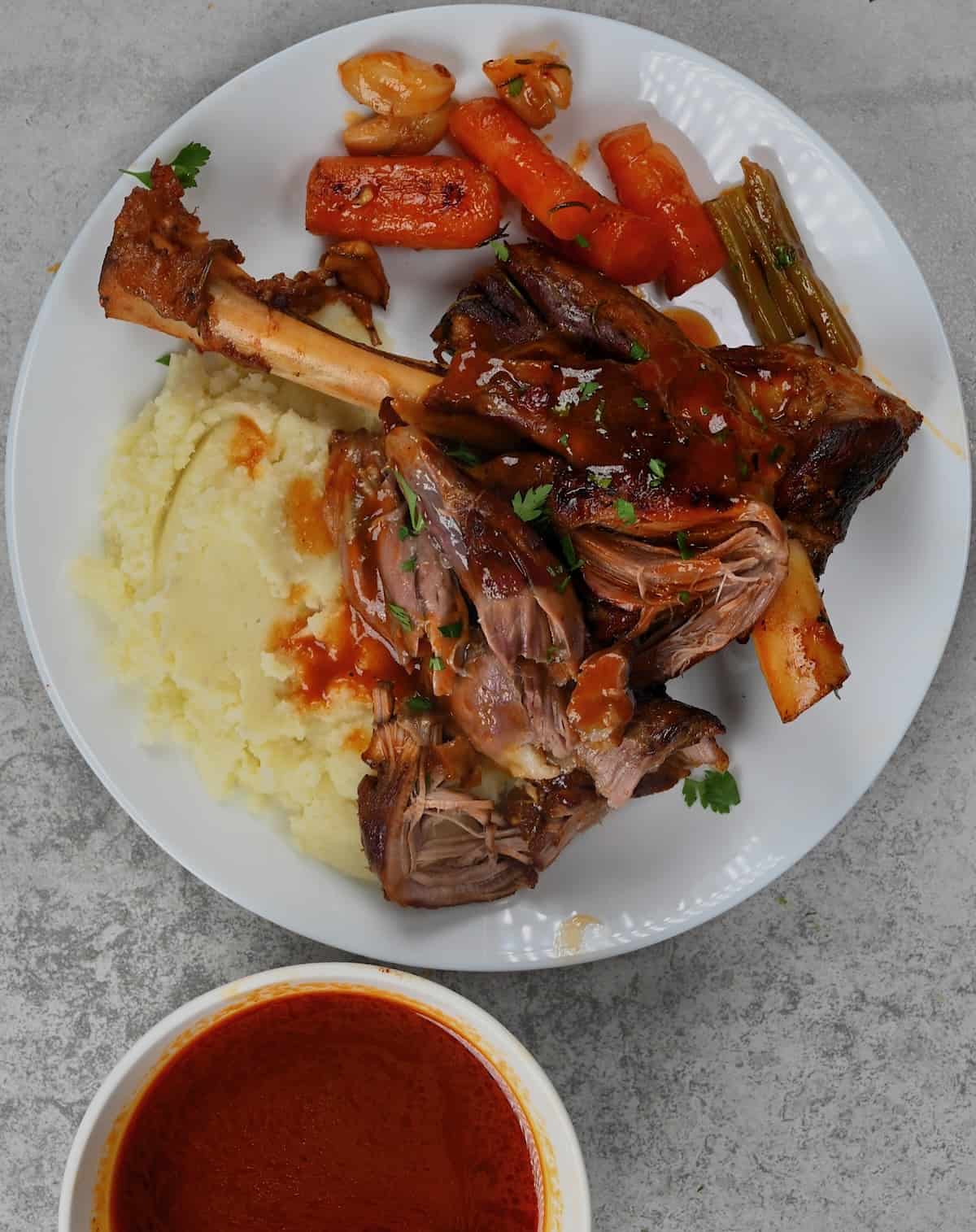 A serving of lamb shank with mashed potatoes