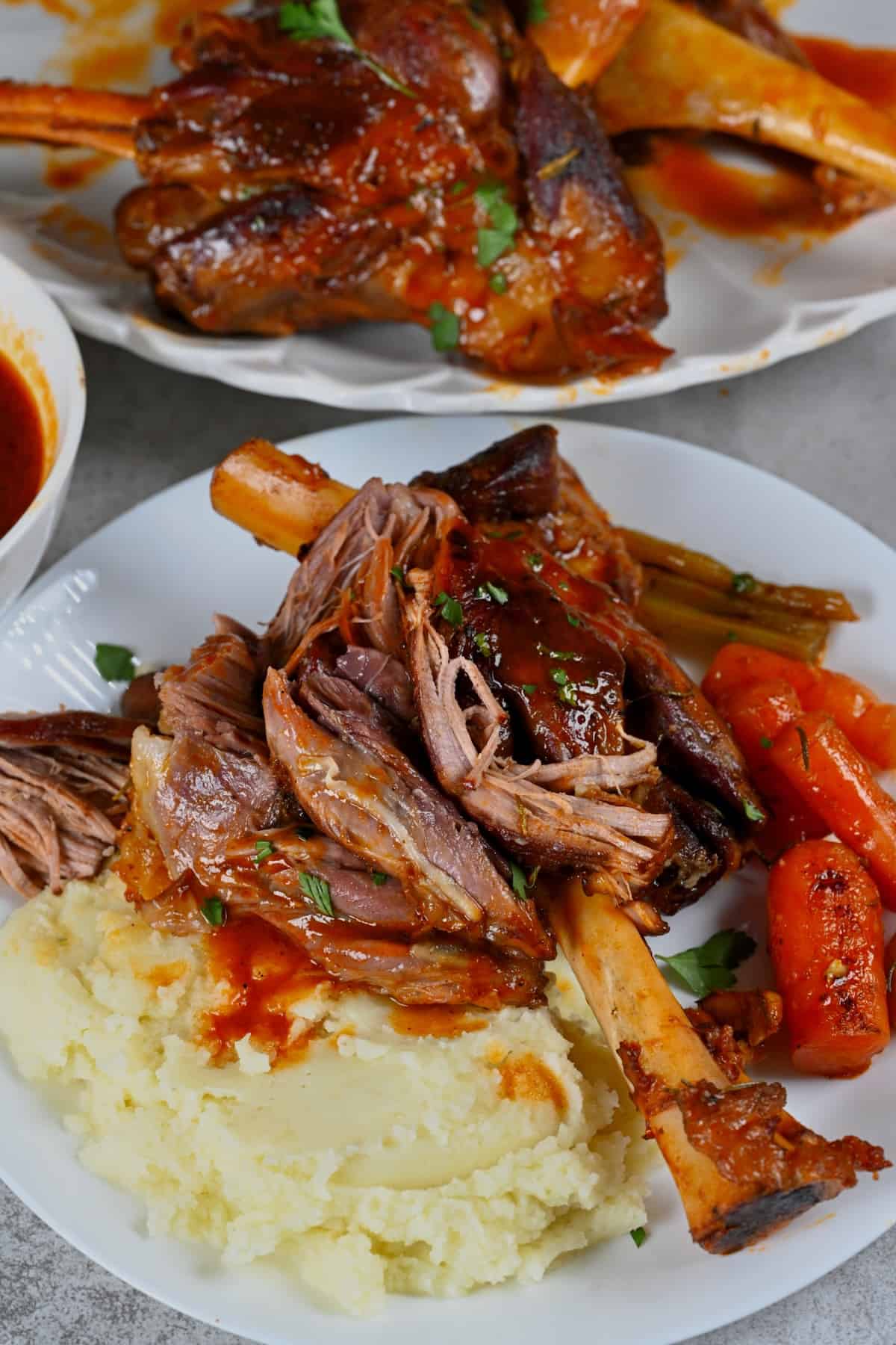 A serving of lamb shank with mashed potatoes