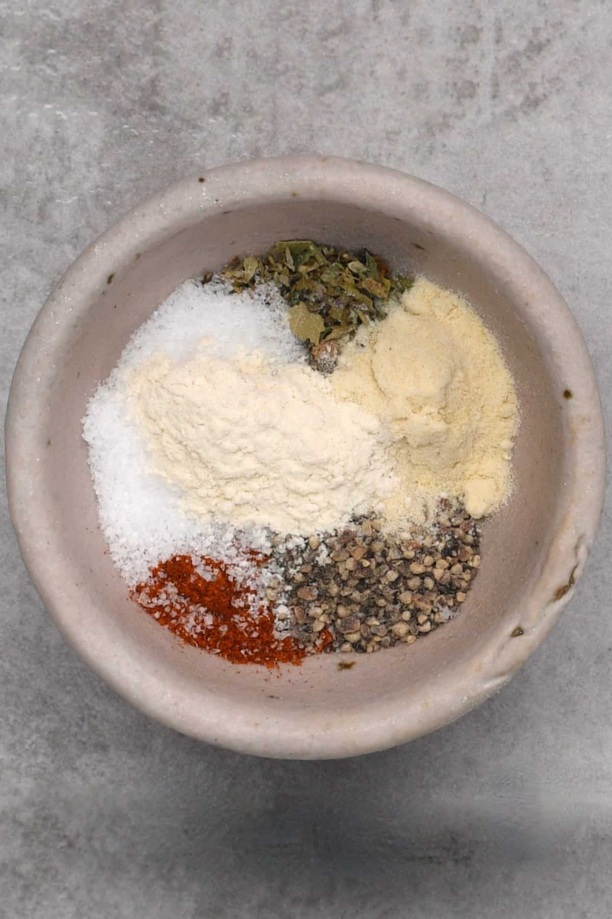A small bowl with chicken seasoning spices