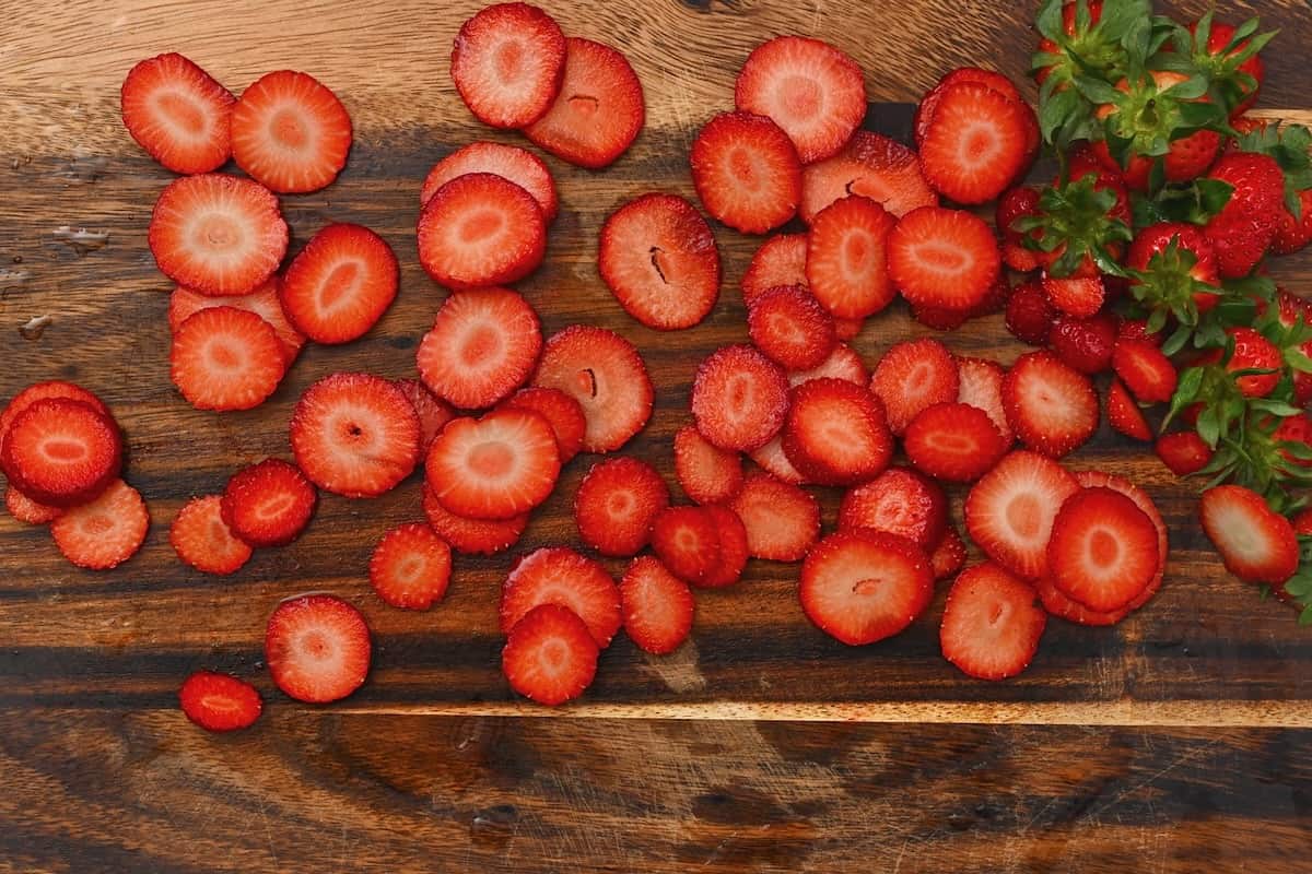 Thinly sliced strawberries on a cutting board