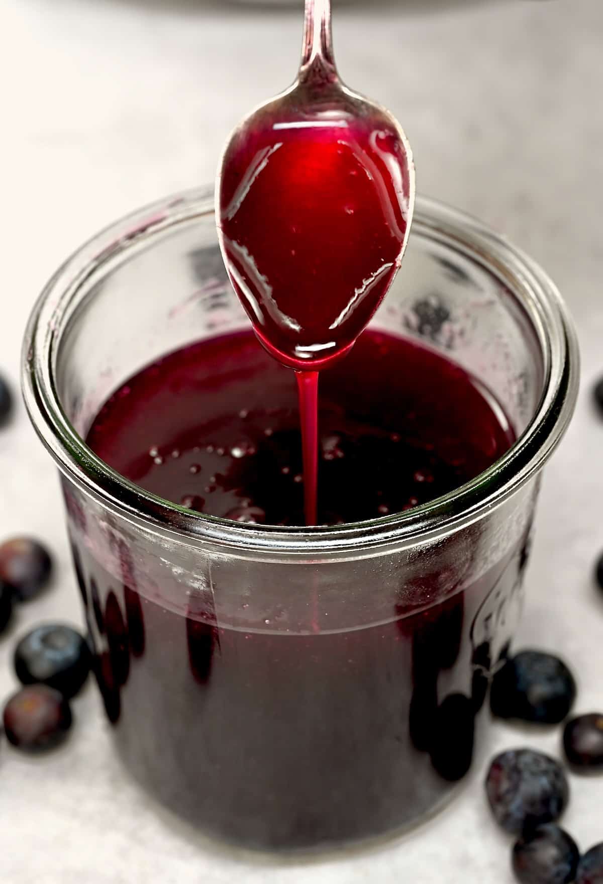 Spooning blueberry syrup over a small jar