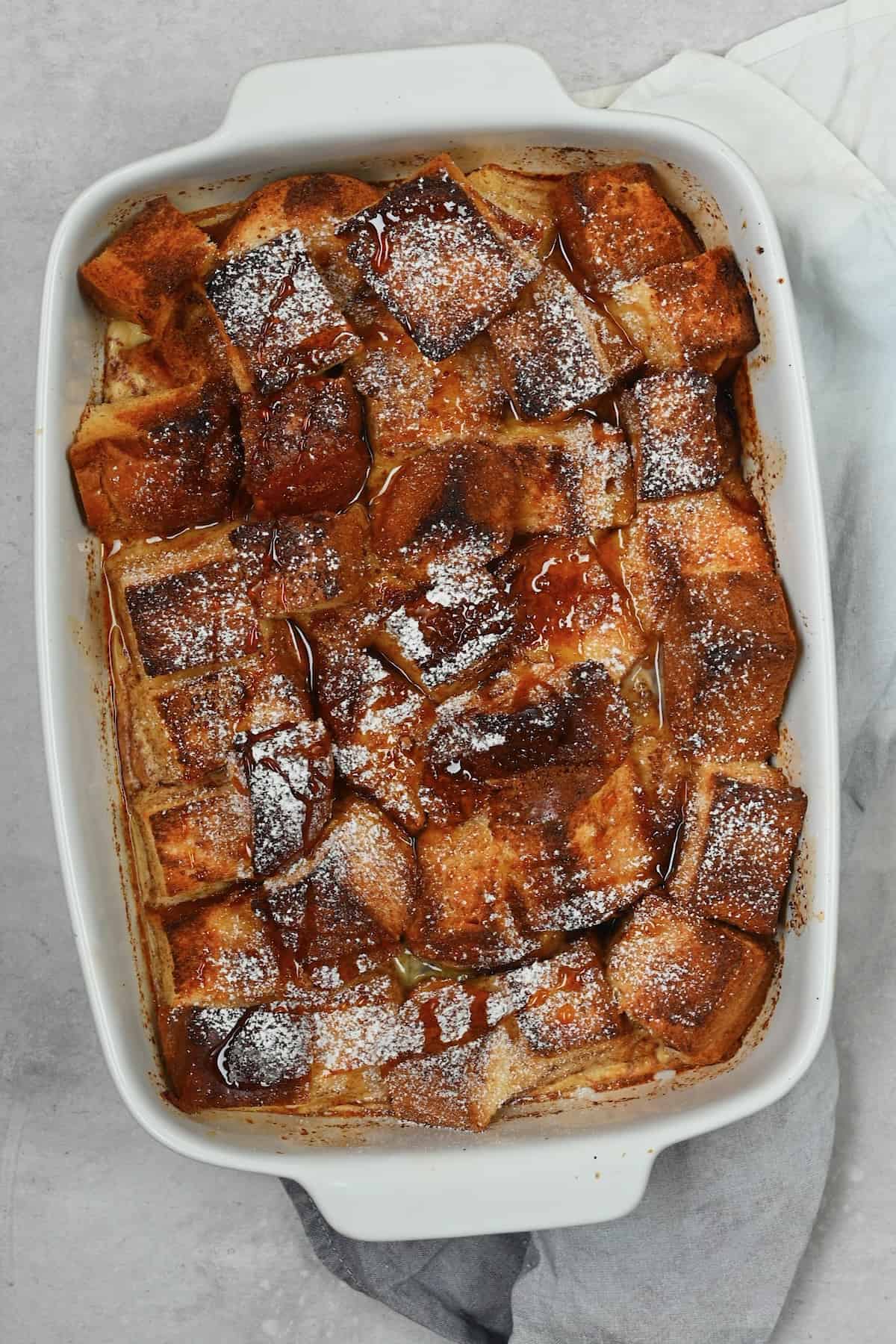 French toast casserole in a baking dish topped with powdered sugar