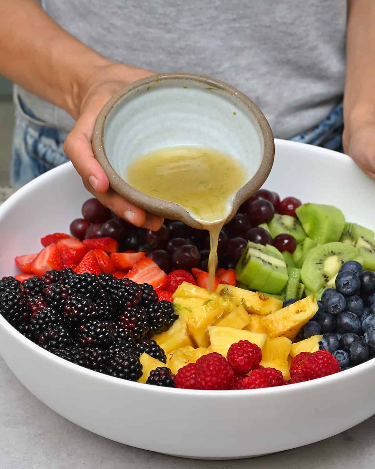 Pouring salad dressing over fruit