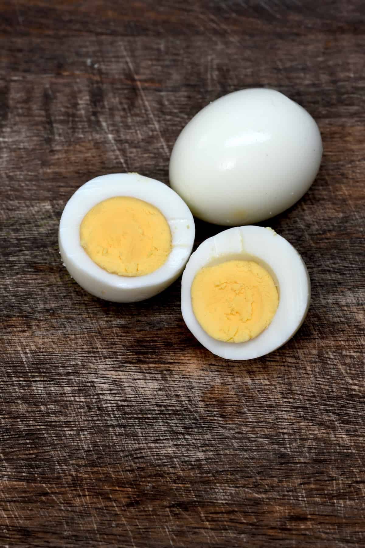 Twp hard boiled eggs, one of which is cut in half