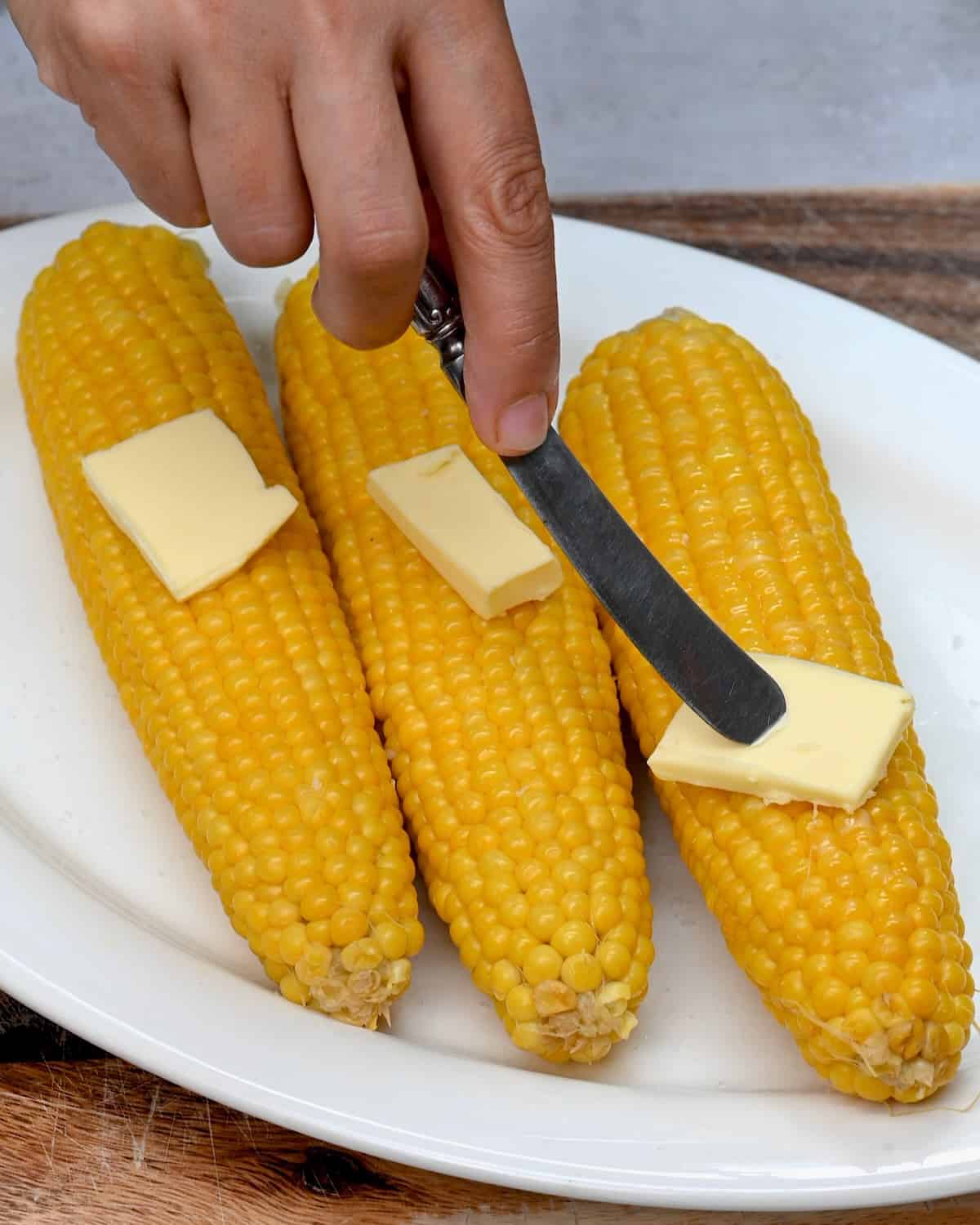 Adding some butter to boiled corn on the cob