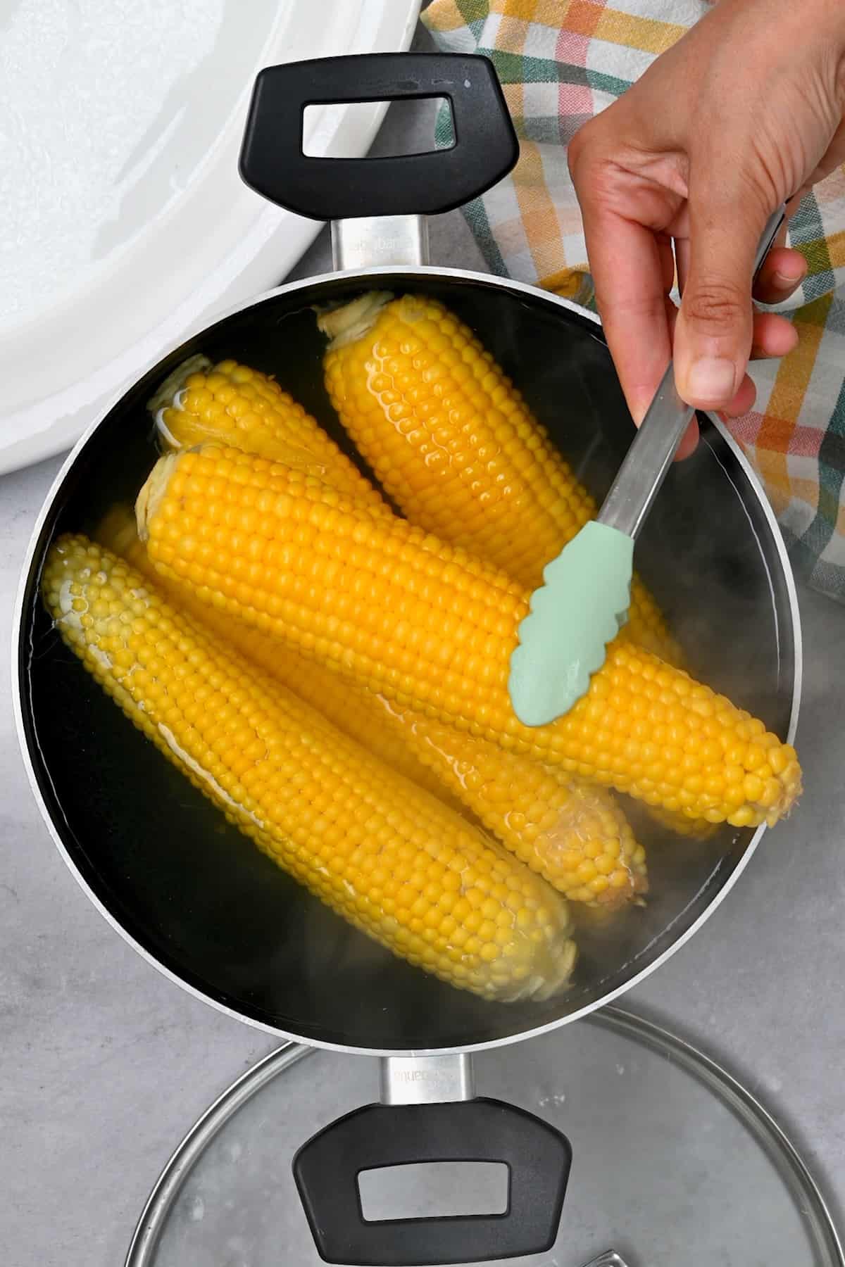 Taking boiled corn out of a large pot