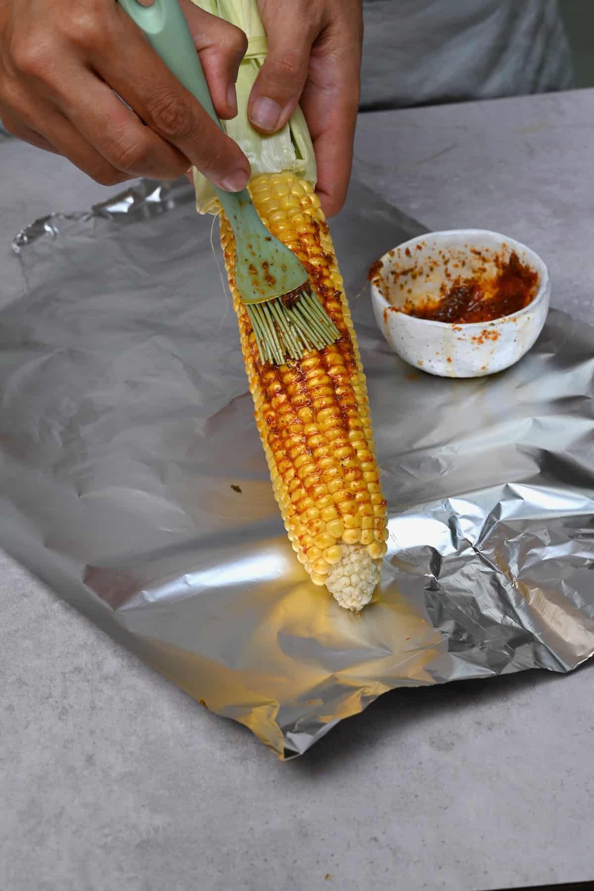 Brushing garlic butter on corn