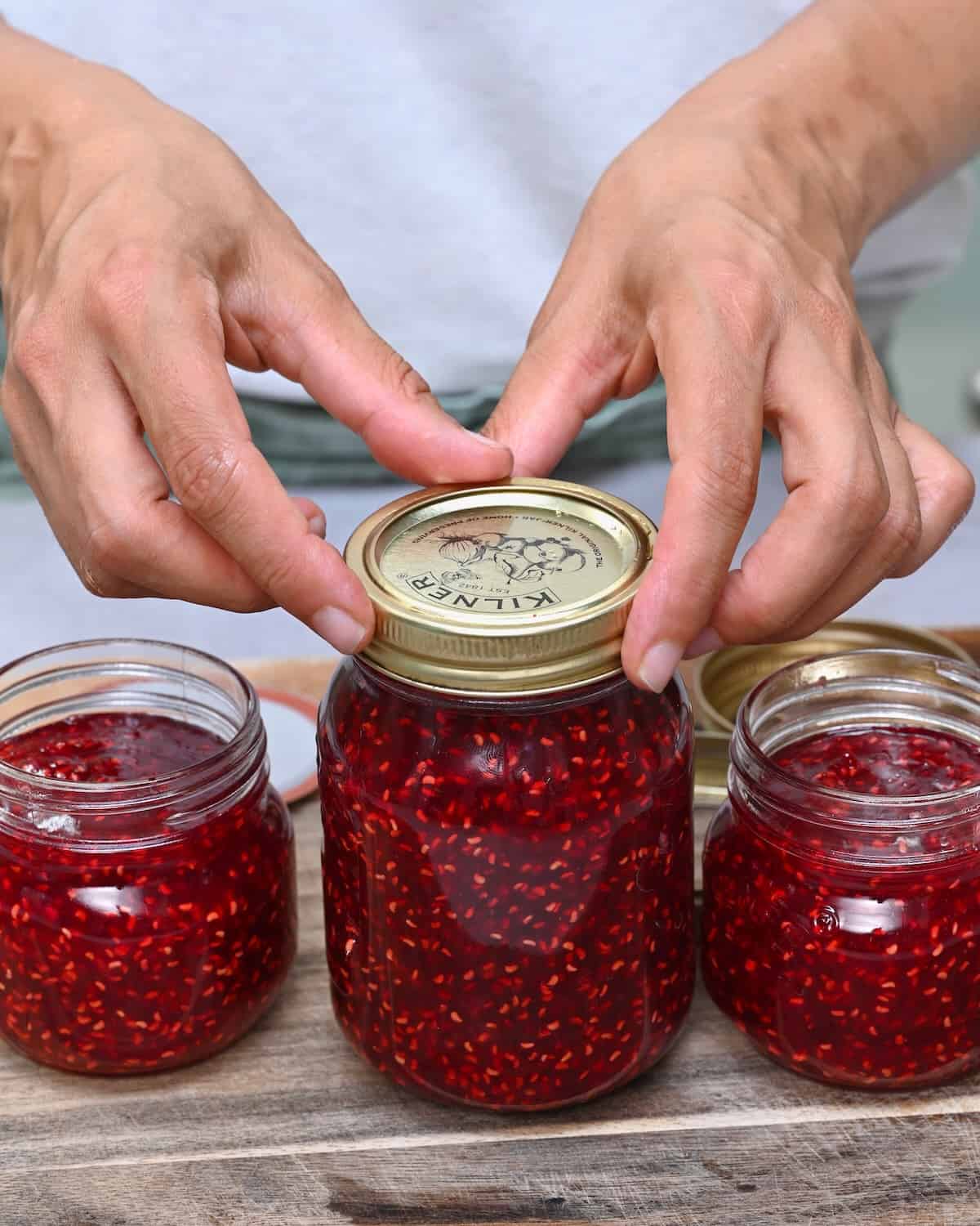 Closing a jar of homemade raspberry jam