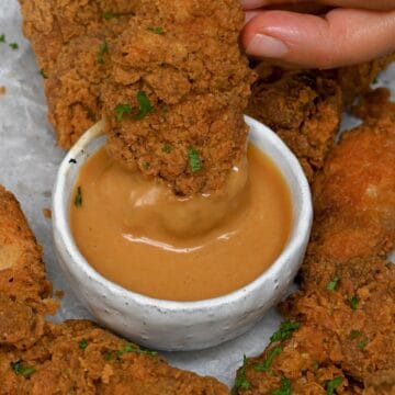 Dipping fried chicken in homemade chick fil a sauce in a small bowl