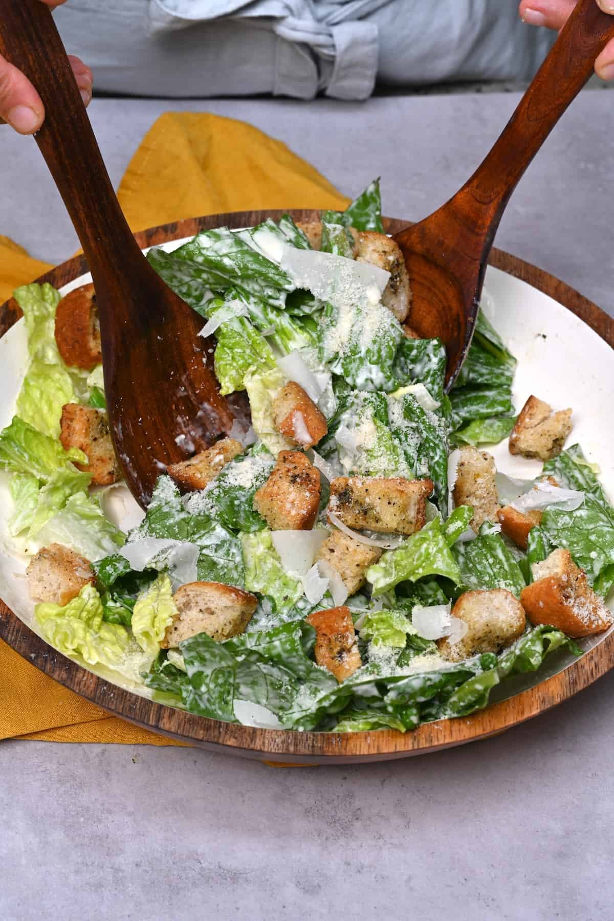 Mixing Caesar salad in a large bowl