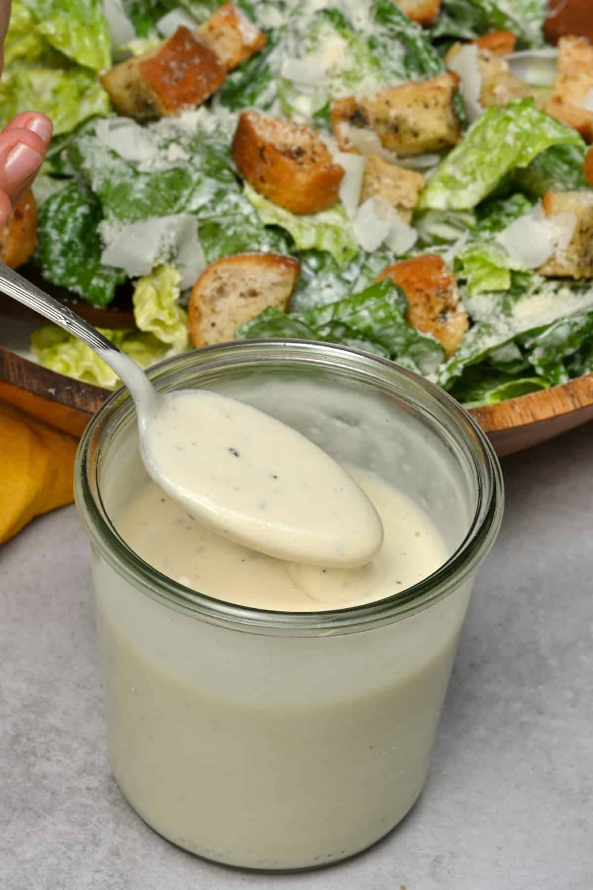 A spoonful of homemade Caesar dressing over a jar