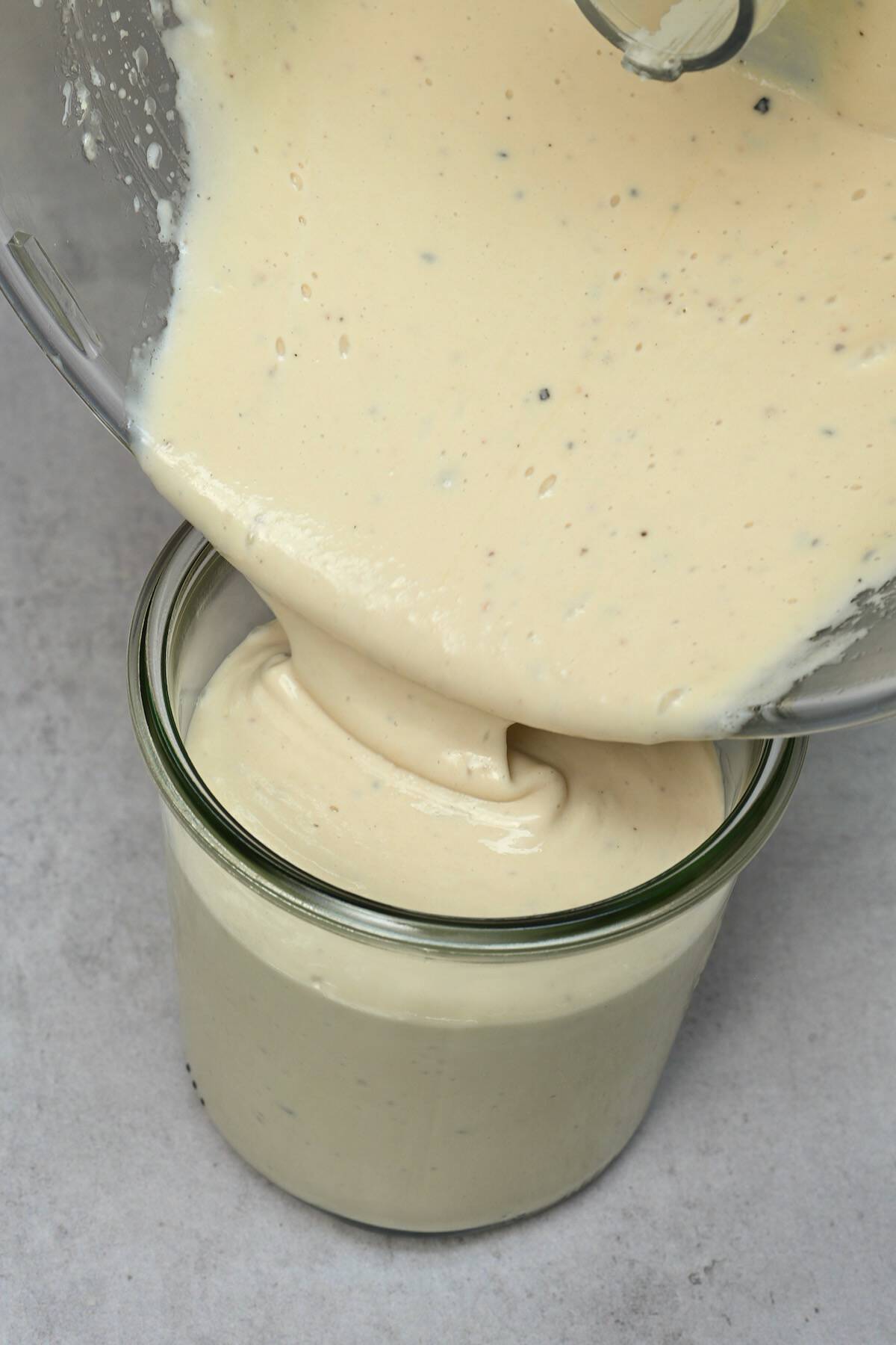 Pouring homemade caesar dressing in a jar