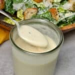 A spoonful of homemade Caesar dressing over a jar