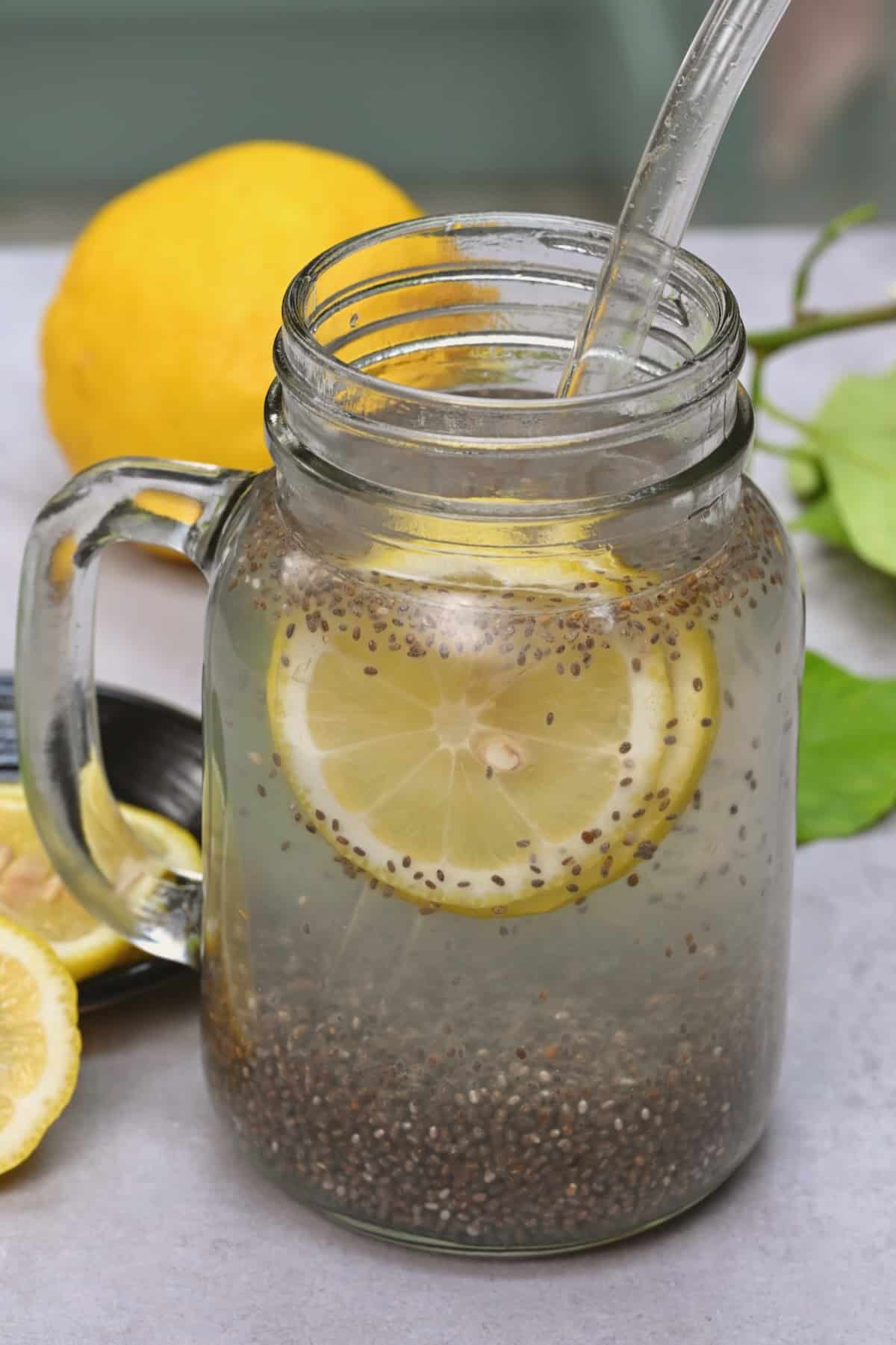 Chia seed water with lemon slices and a glass straw in a mason jar