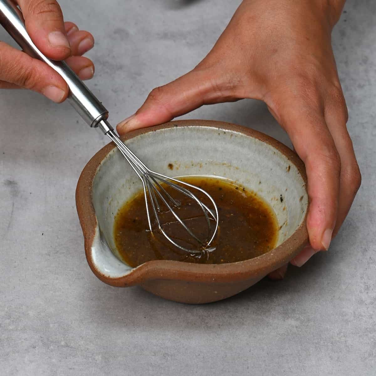Whisking oil with balsamic vinegar in a bowl