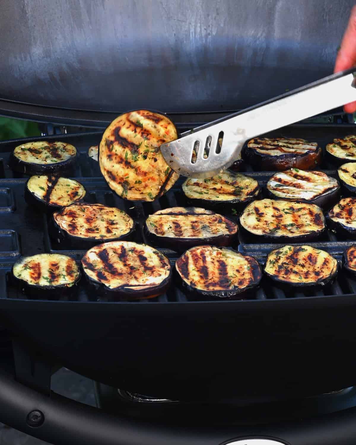 Removing cooked eggplant slice from the grill