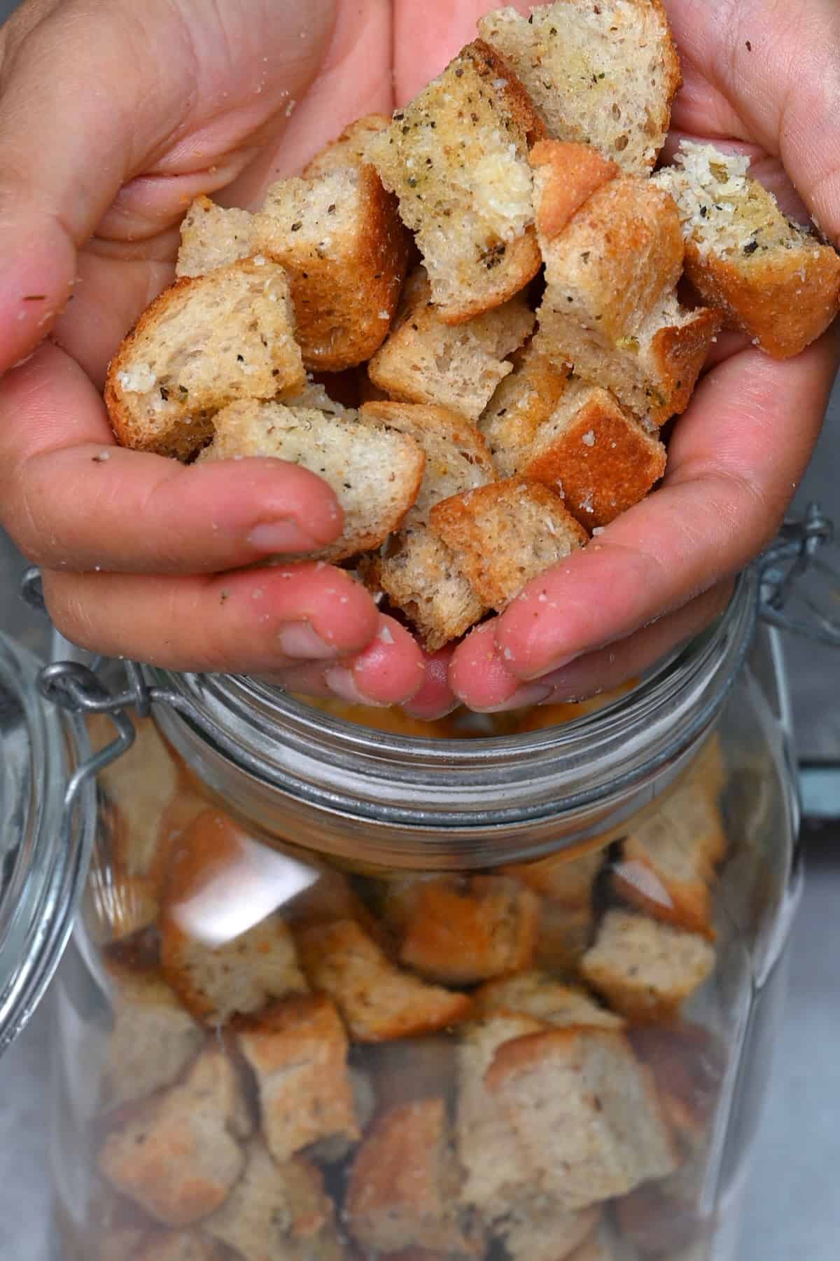 Placing homemade croutons in a jar