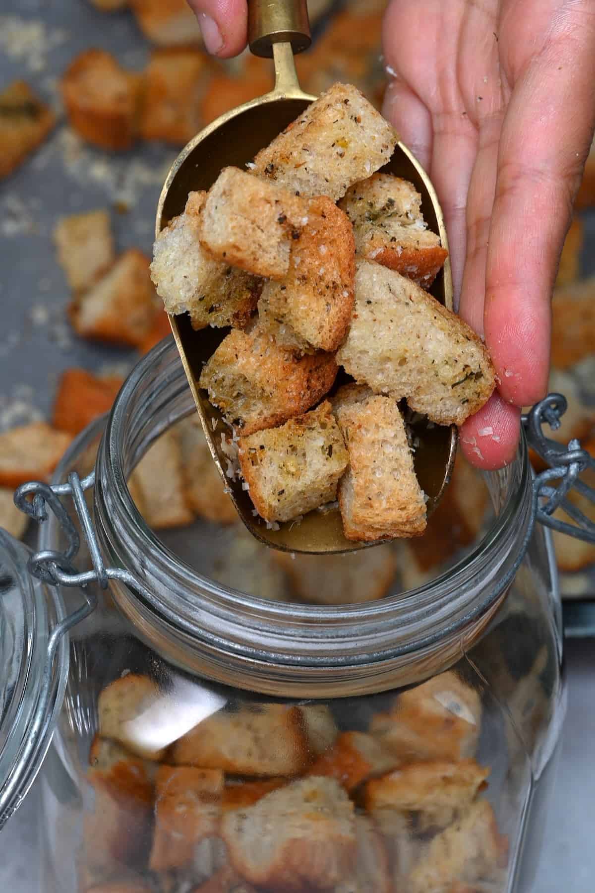 Placing homemade croutons in a jar