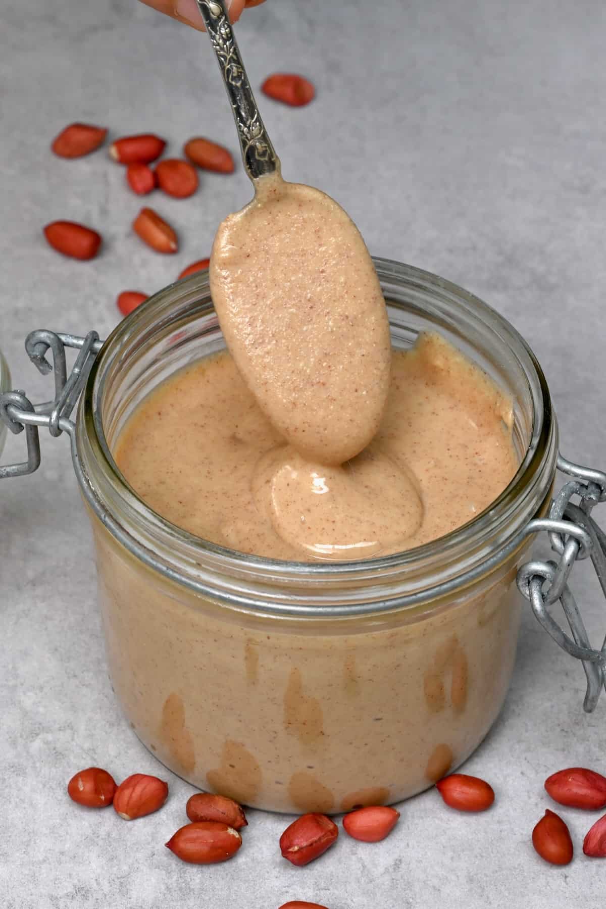 Drizzling peanut butter from a spoon to a jar
