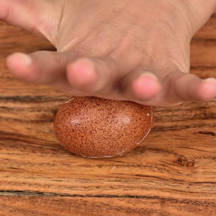 Rolling a boiled egg on a board to break the shell