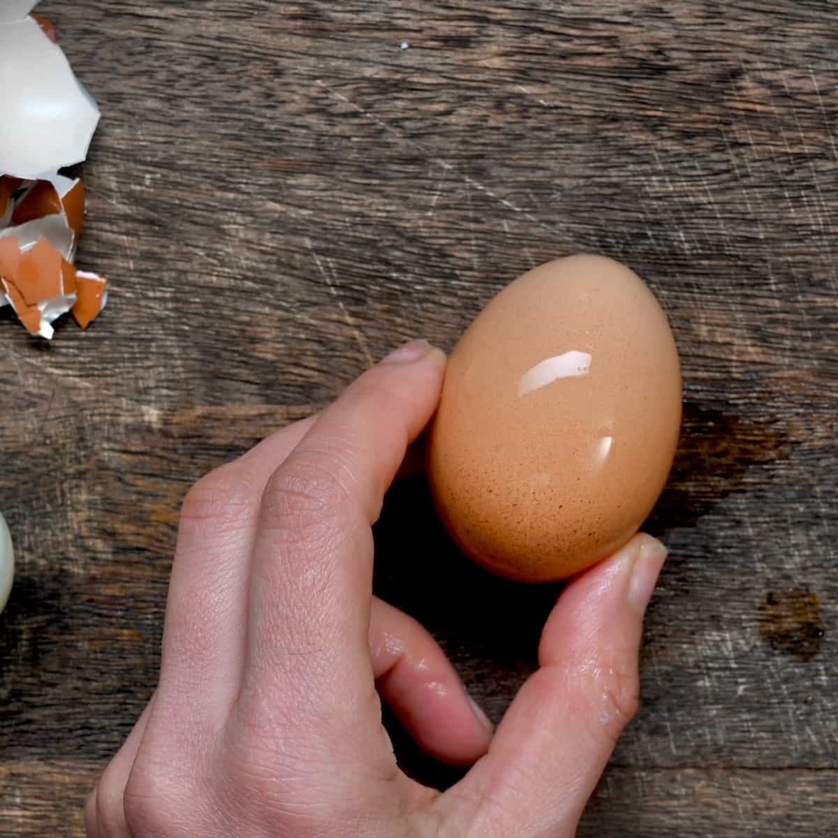 Tapping a boiled egg on a board to break the shell