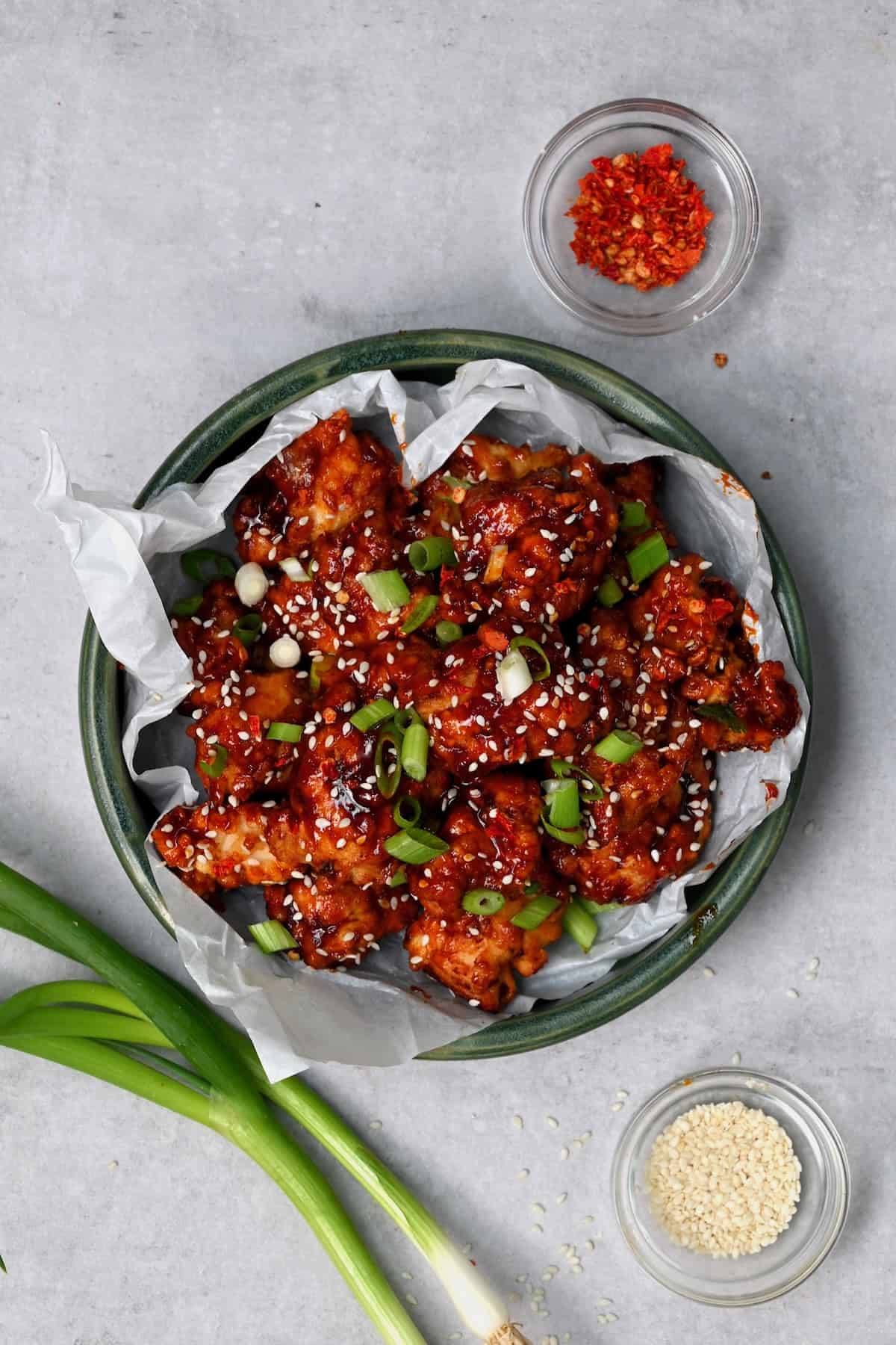 Korean fried chicken topped with sesame seeds and spring onions