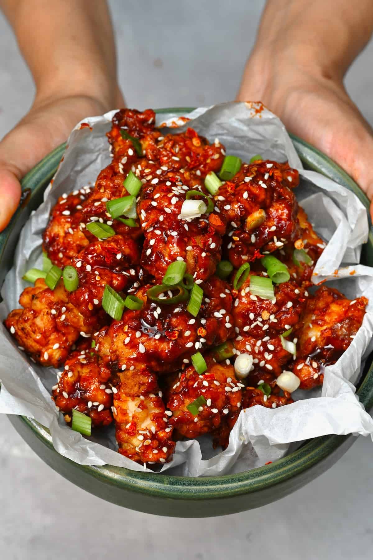 A serving of Korean fried chicken topped with sesame seeds and spring onions