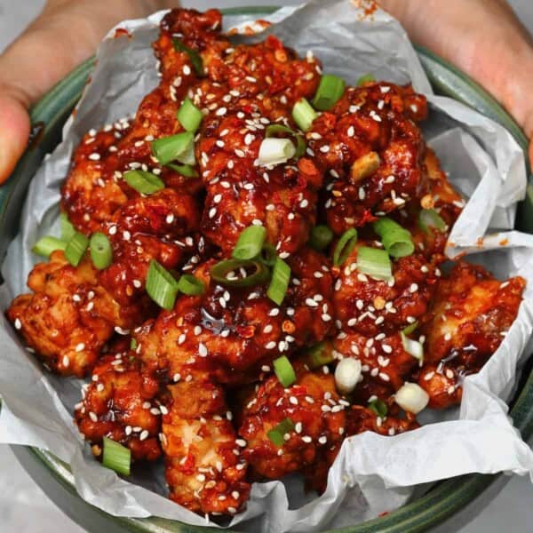 A serving of Korean fried chicken topped with sesame seeds and spring onions