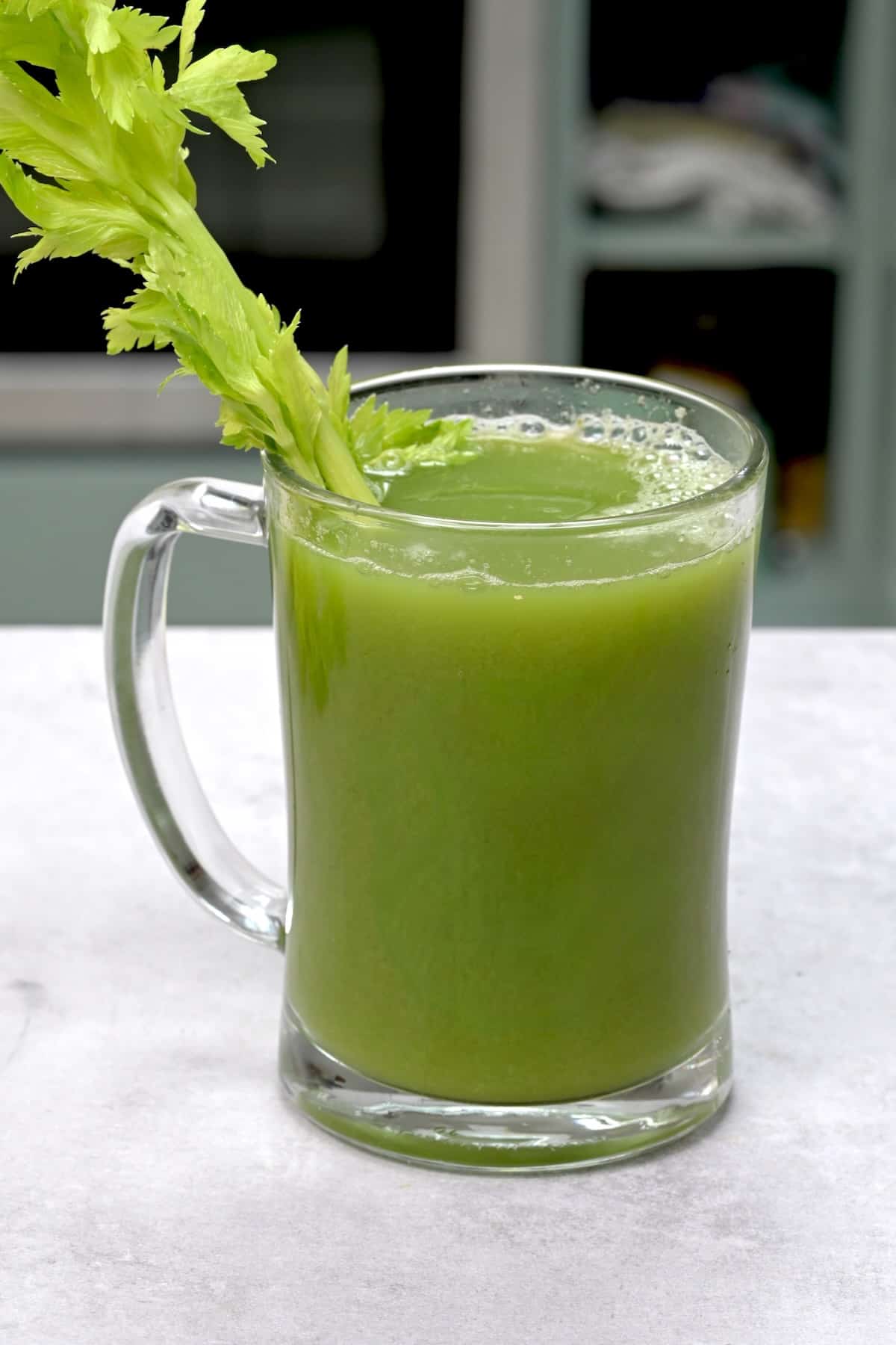 A glass of celery juice and a celery stalk