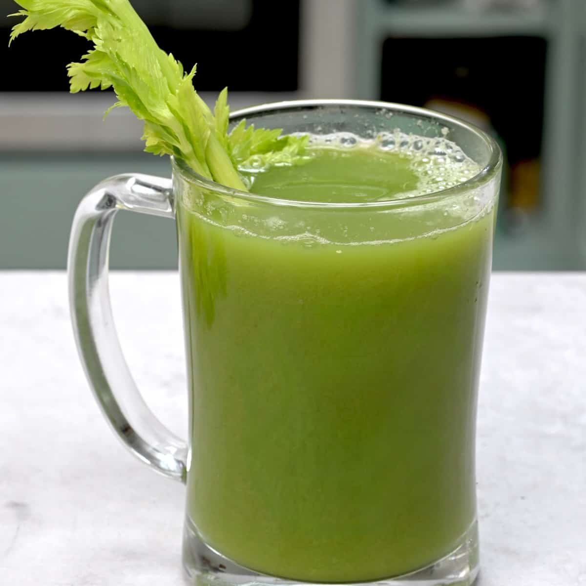 A glass of celery juice and a celery stalk