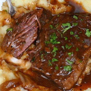 A serving of mashed potatoes with steak and gravy