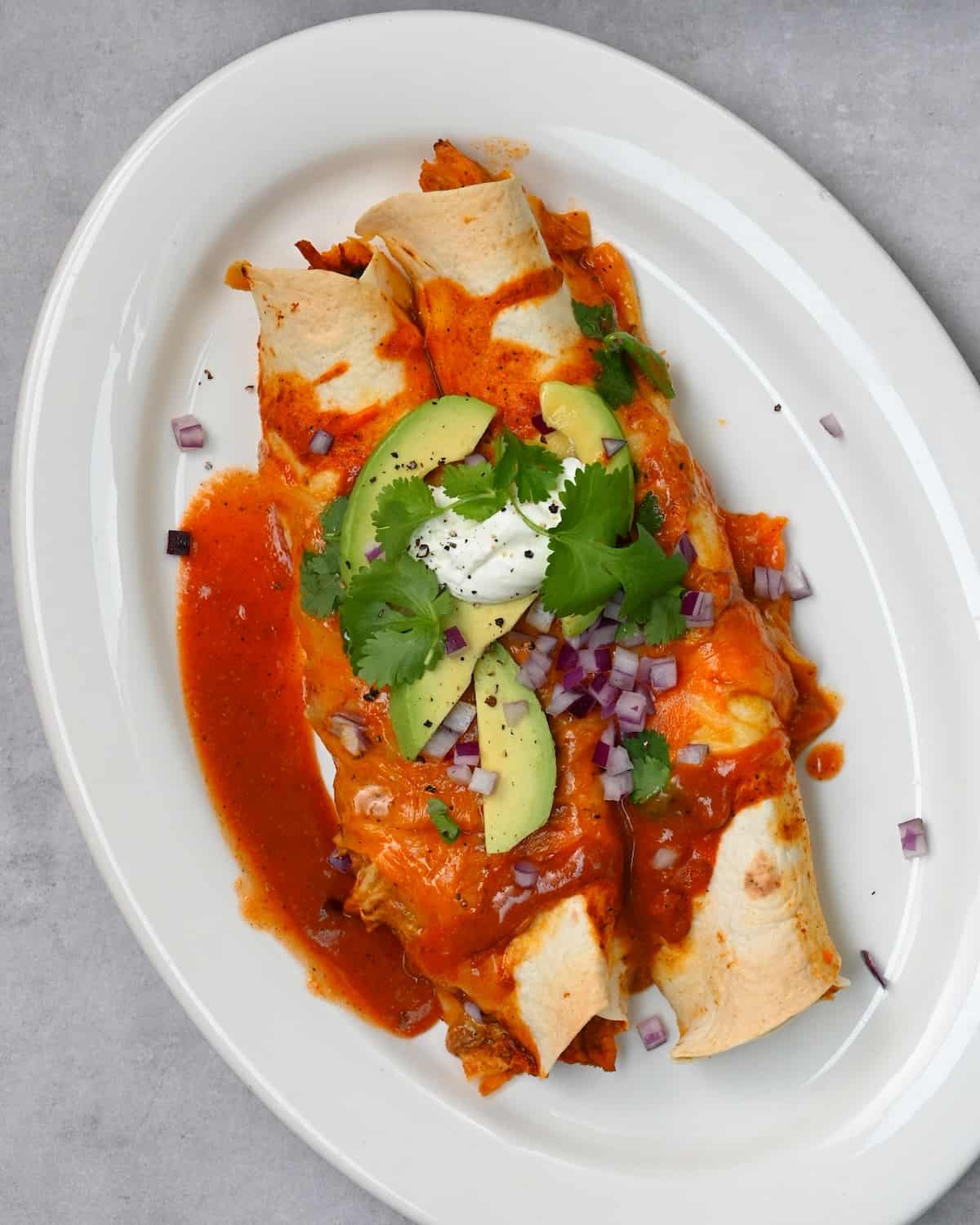 A serving of chicken enchilada topped with avocado