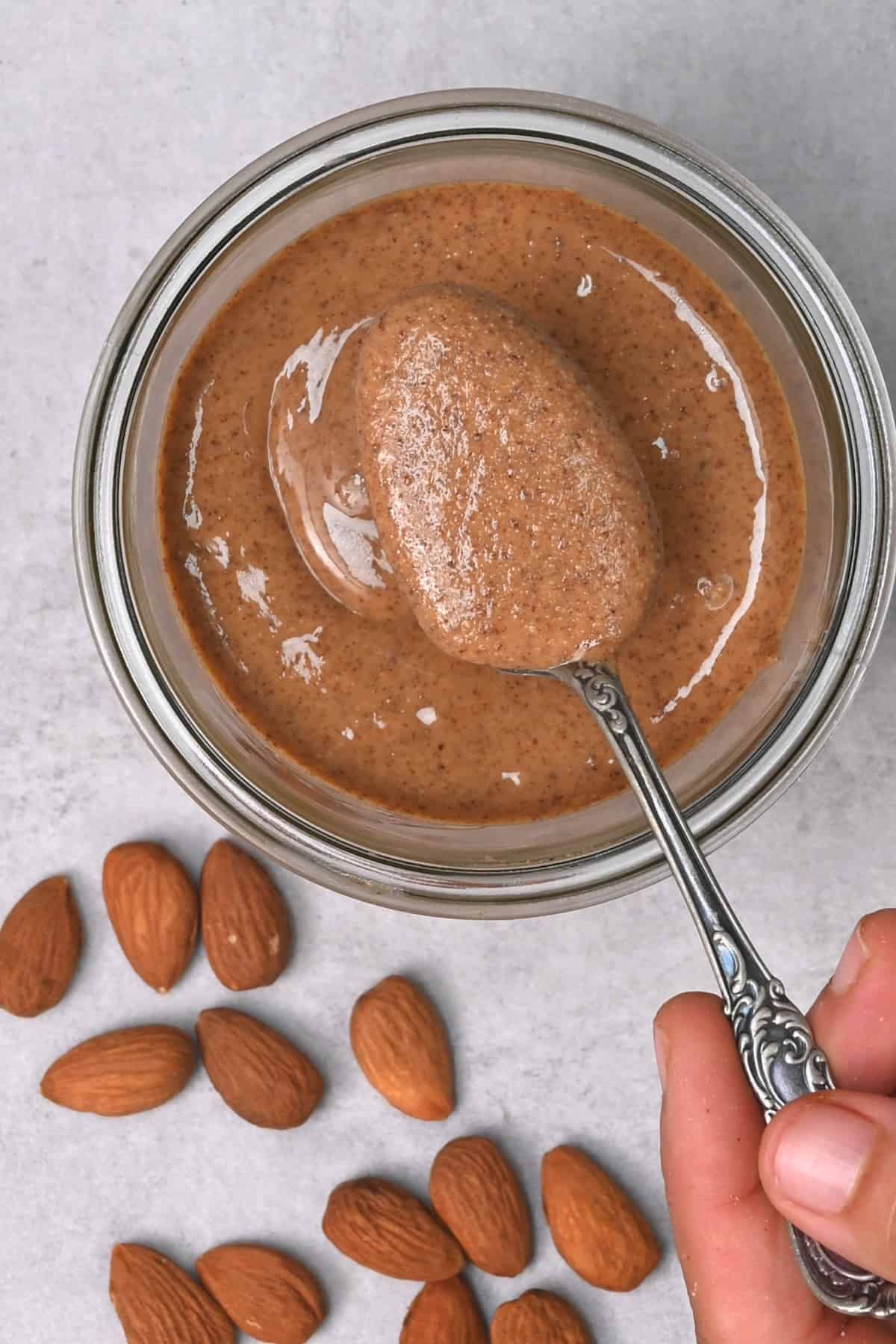 A spoonful of homemade almond butter over a jar