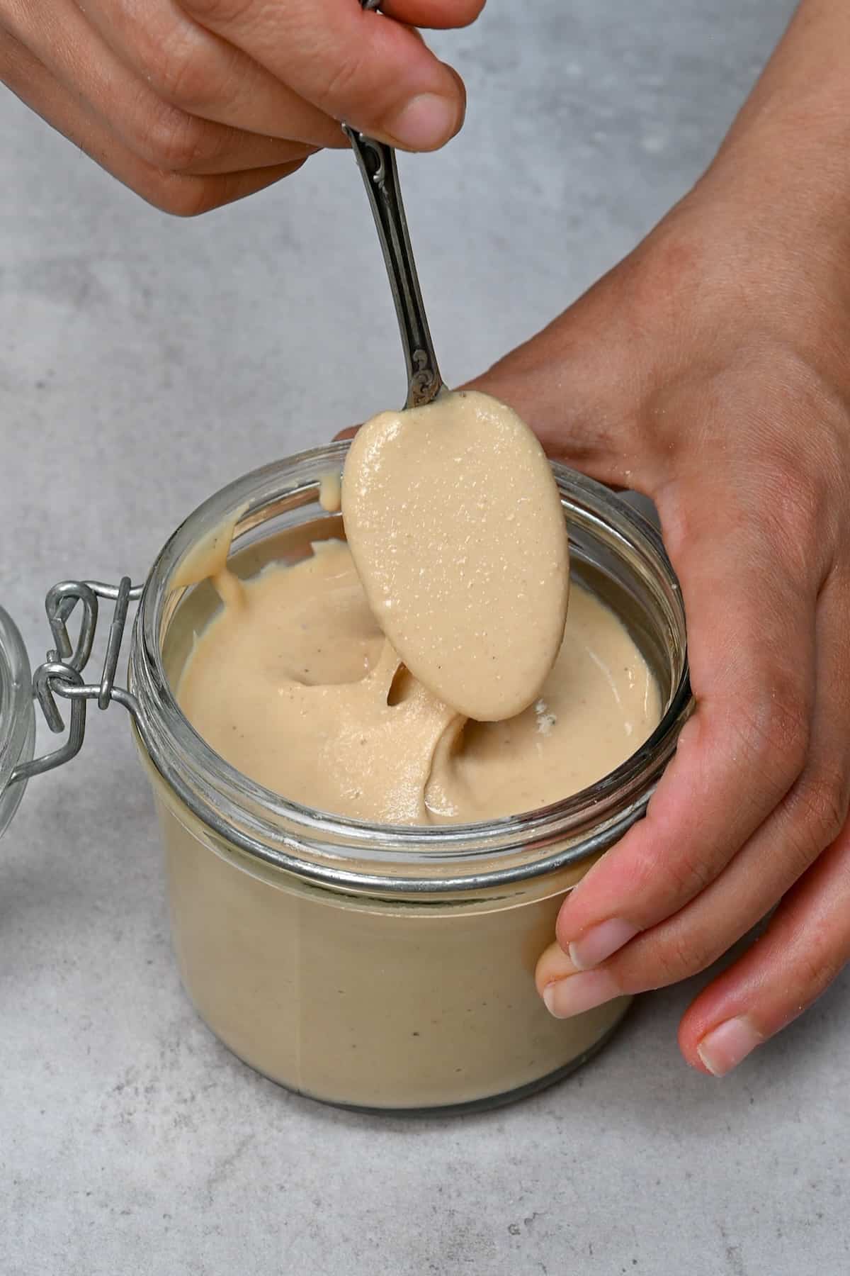 A spoonful of homemade cashew butter over a jar
