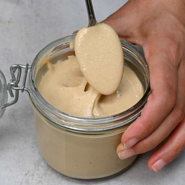 A spoonful of homemade cashew butter over a jar