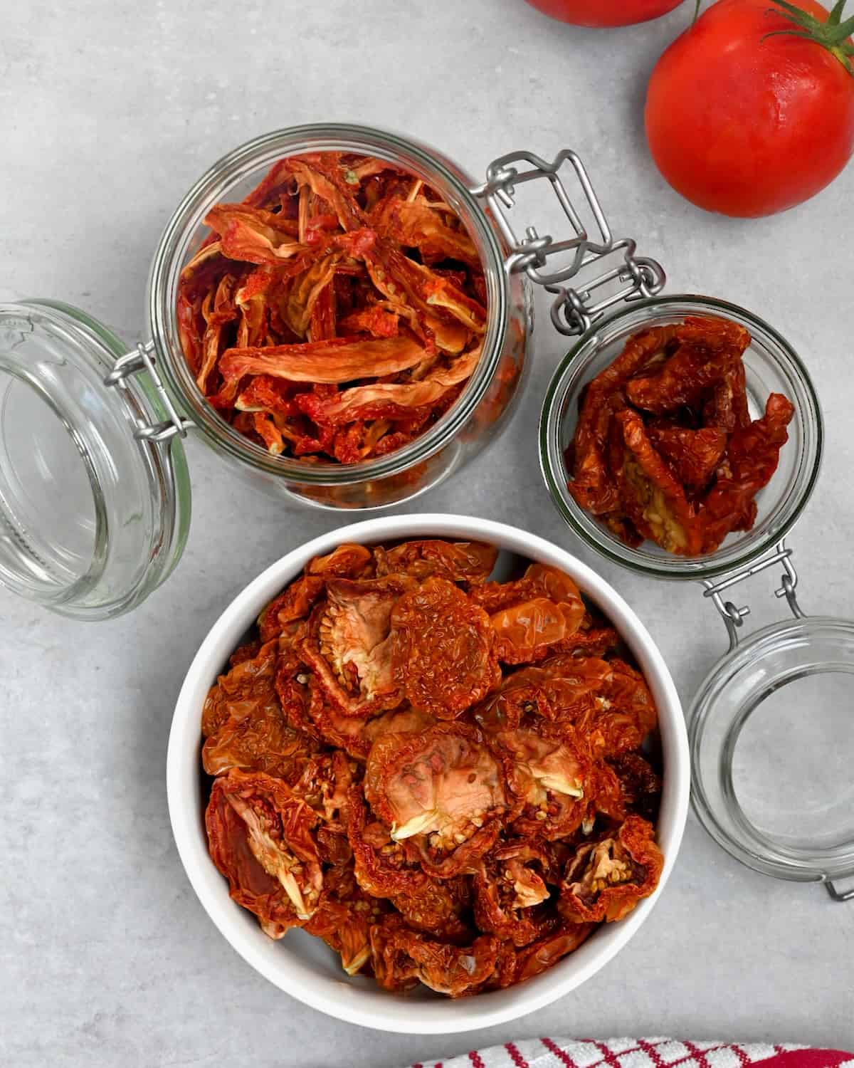 Sun dried tomatoes in a bowl and in two jars