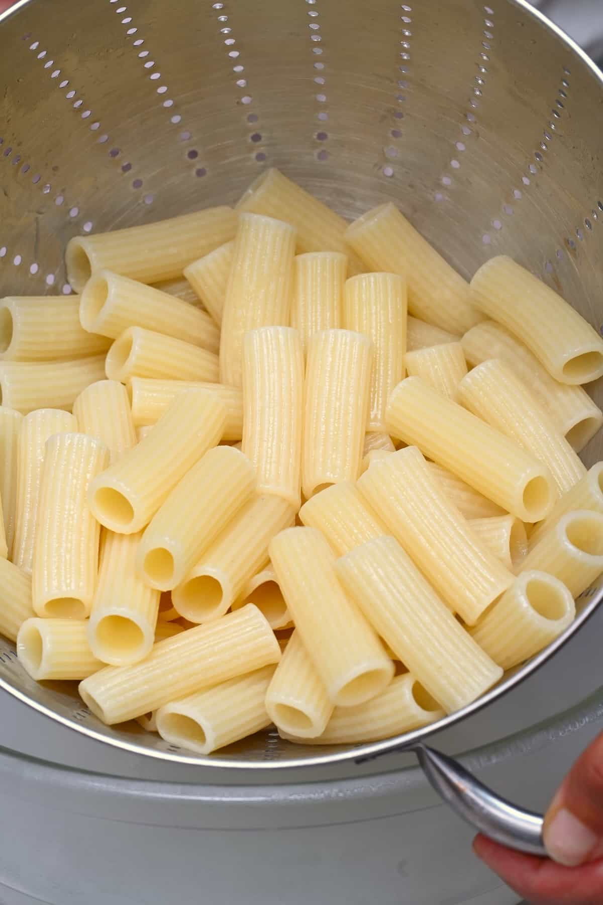 Cooked rigatoni pasta in a colander
