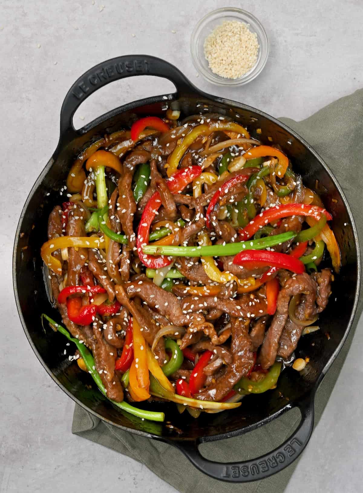 Beef stir fry sprinkled with sesame seeds in a wok