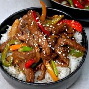 A serving of beef stir fry over rice sprinkled with sesame seeds