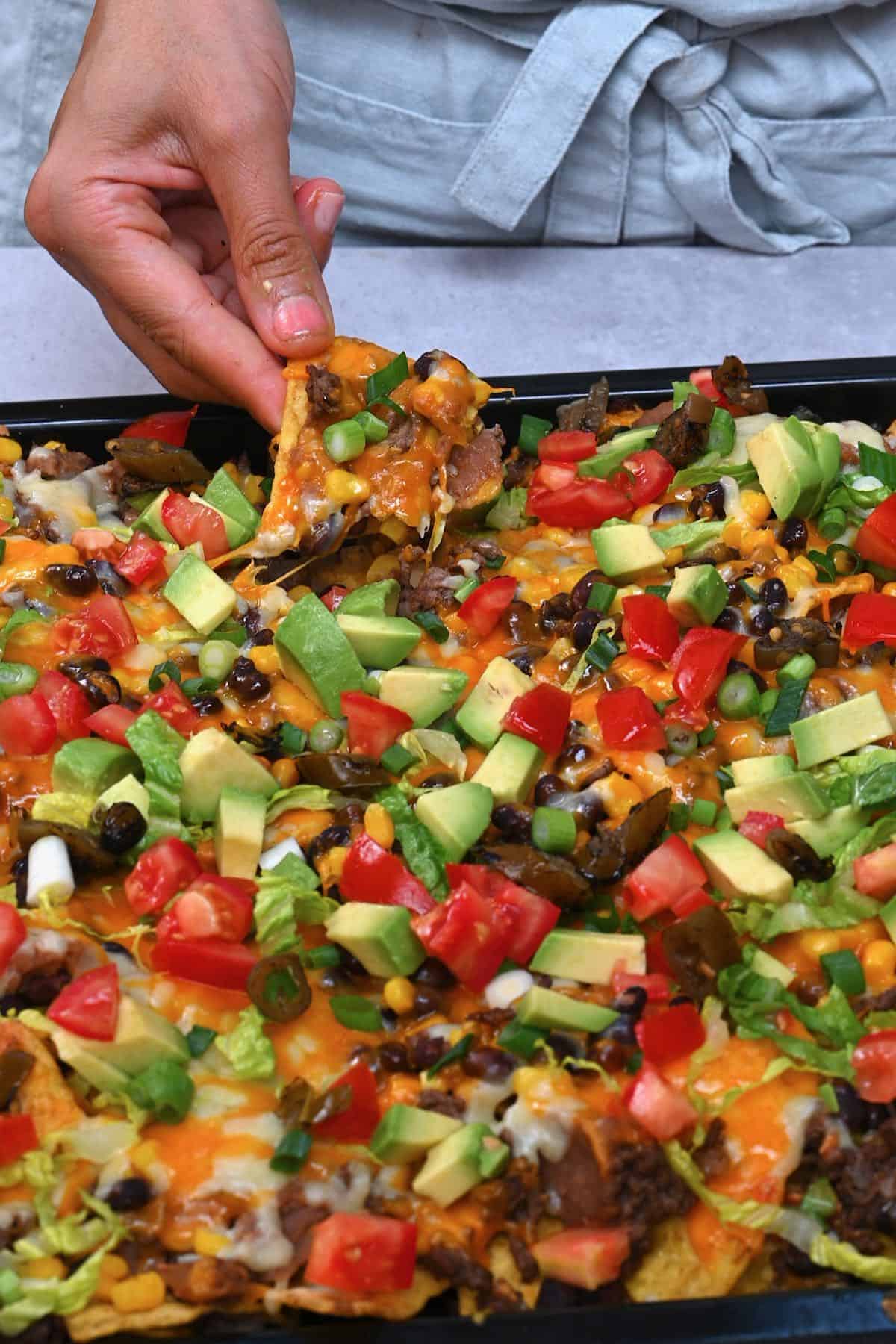 hand holding Nachos from an oven tray