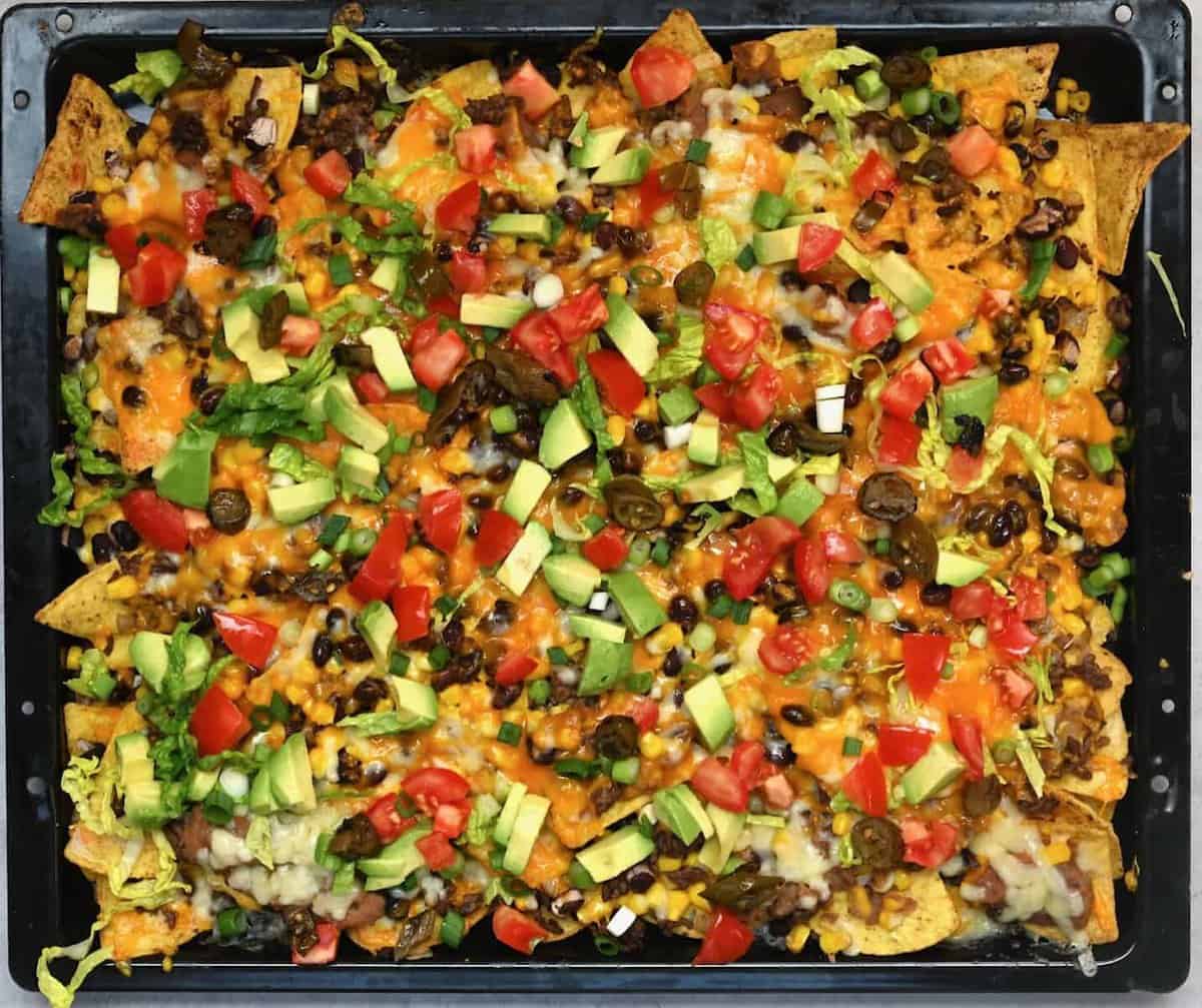 Nachos with toppings on an oven tray