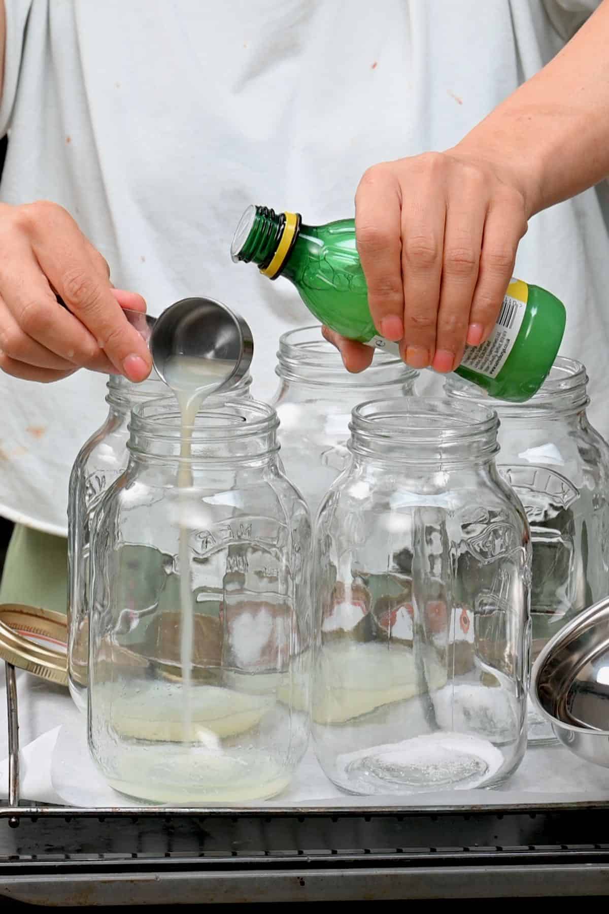 adding bottled lemon juice and salt to glass jars for canning