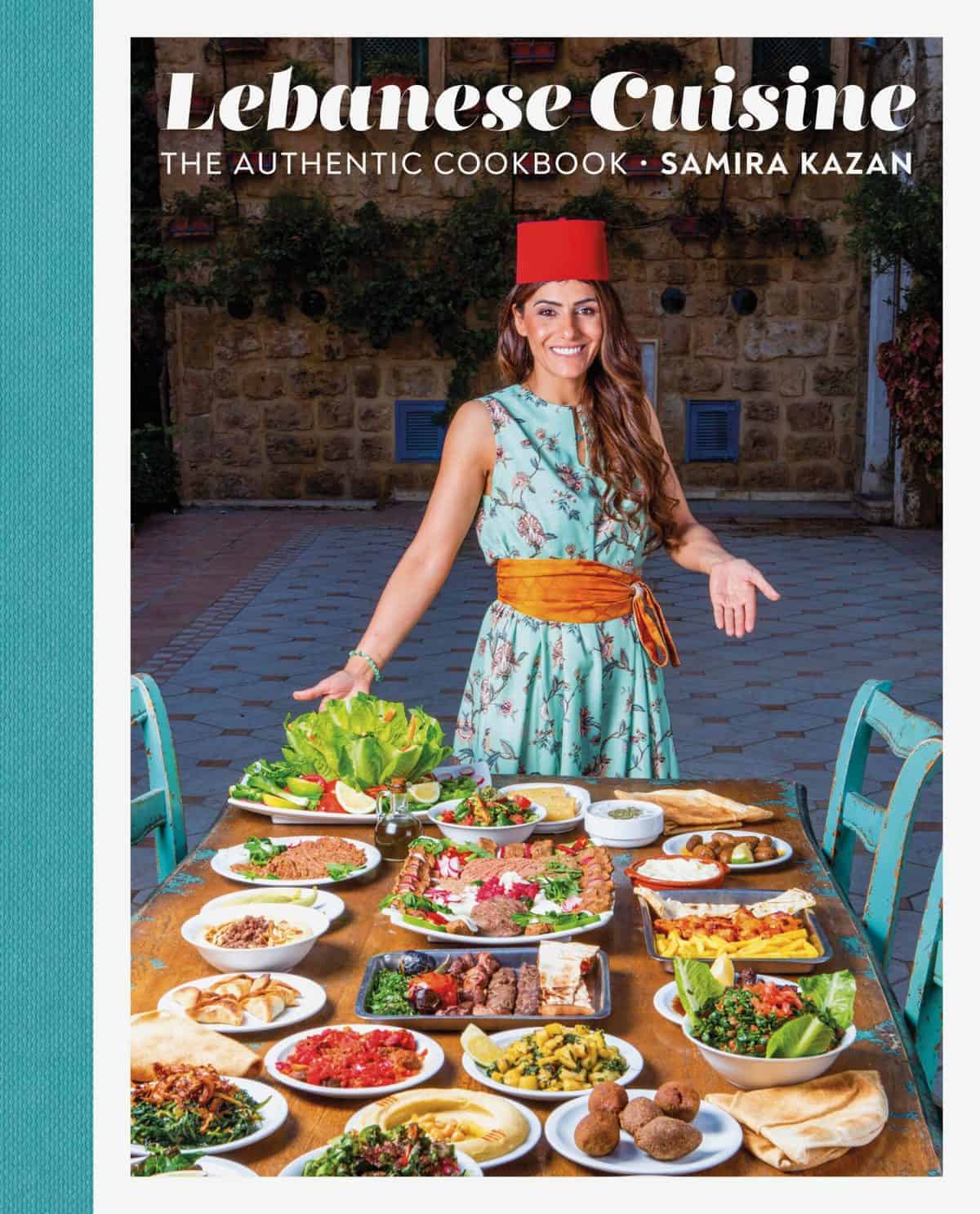 The book cover of Lebanese Cuising shows author Samira Kazan in front of a table set with many Lebanese dishes.