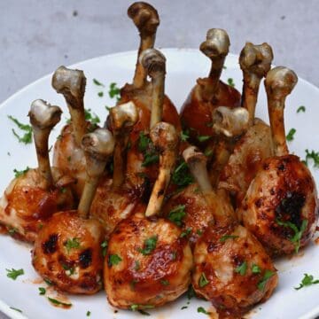 chicken lollipops on a white plate with sprinkle of parsley