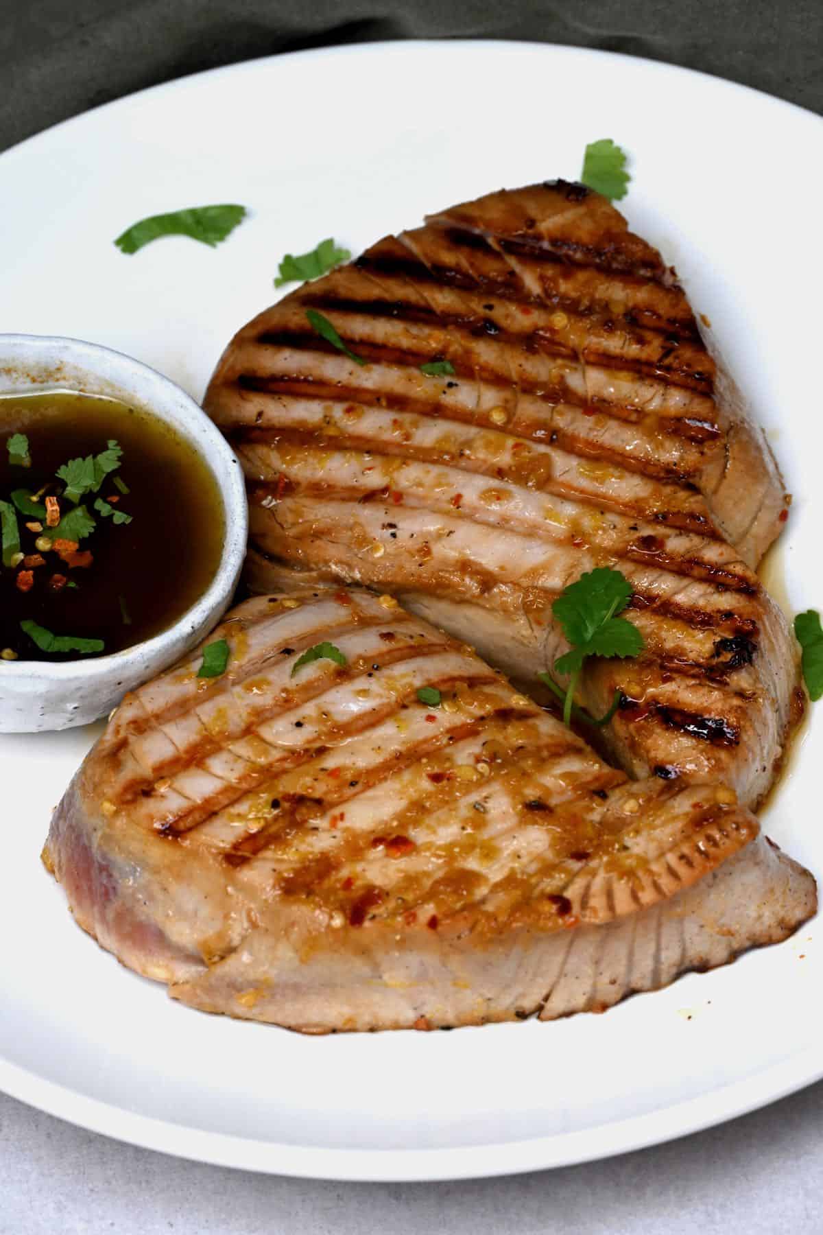 grilled tuna steaks on a plate with sauce