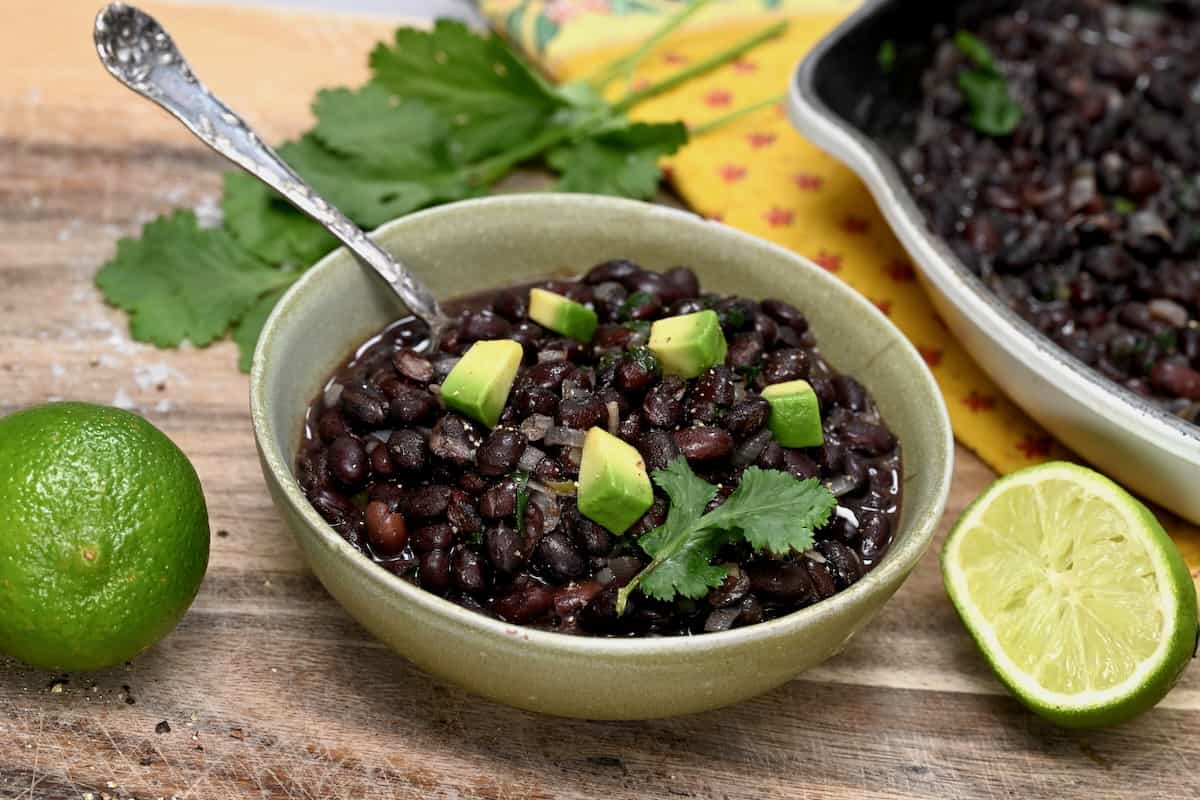 A serving of Mexican black beans topped with avocado pieces