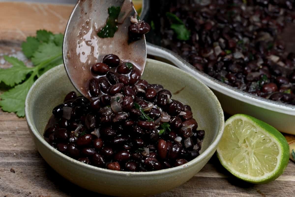 Adding a serving of black beans to a bowl