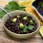 A serving of Mexican black beans topped with avocado pieces