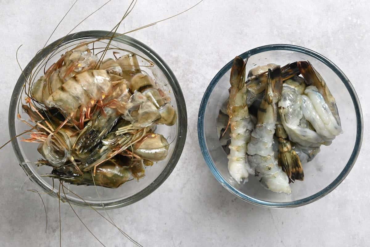 Two bowls: one with cleaned shrimp, and another with leftover shells and heads.